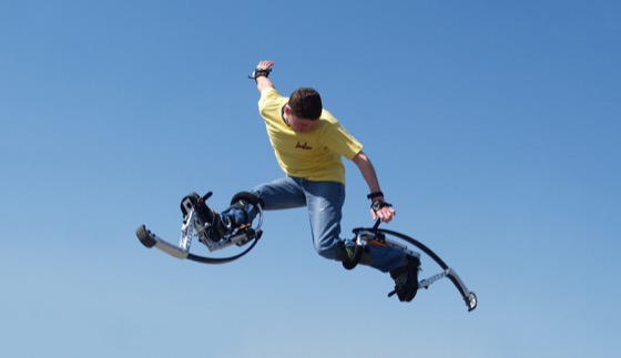 Eine Person schwebt auf Skyrunner-Sprungstelzen vor klarem blauem Himmel in der Luft