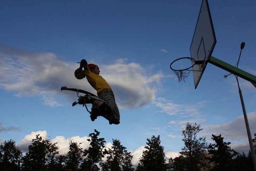 Eine Person mit Helm und Schonern versenkt auf Sprungstelzen einen Basketball